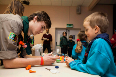 A Young Leader helps a Beaver Scout with a craft activity.
